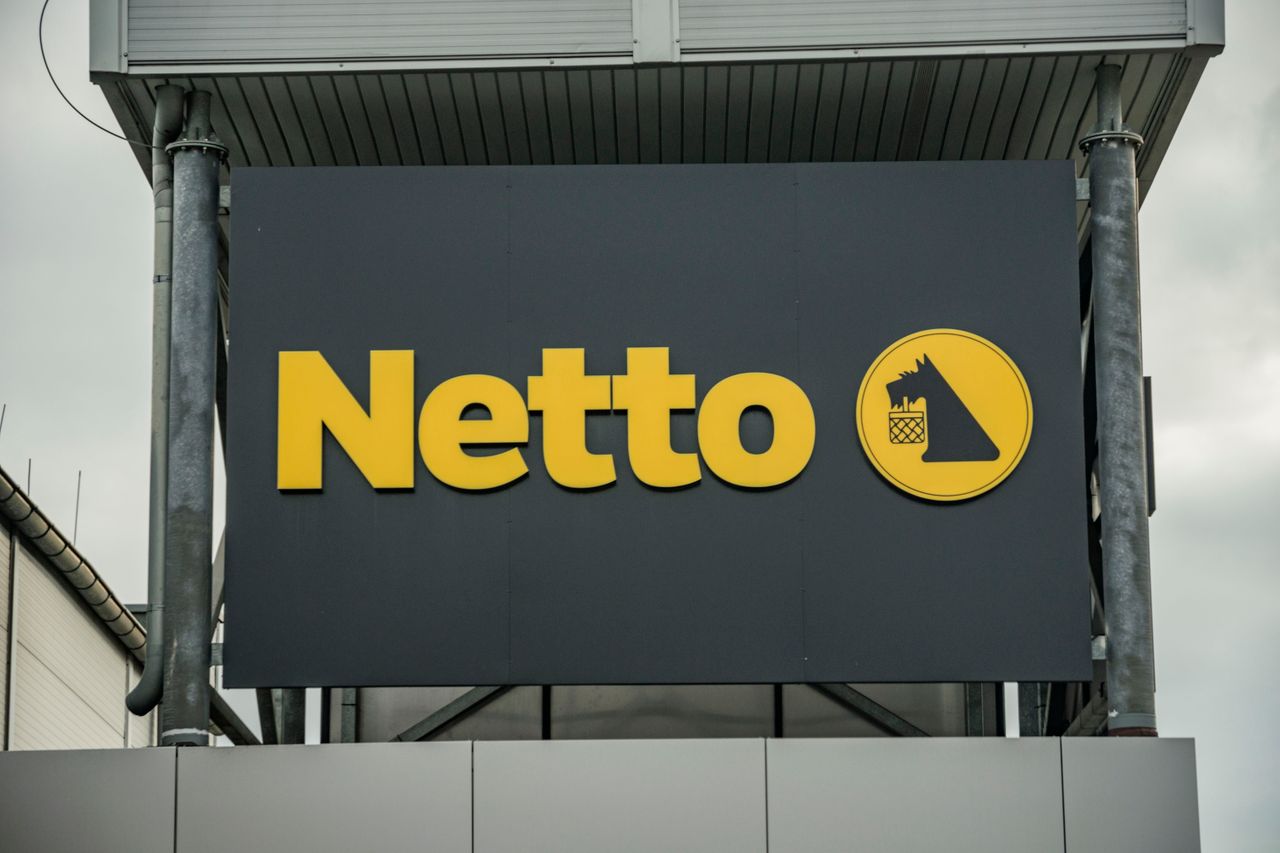 Exterior view of Netto supermarket branding, featuring yellow logo on dark background.
