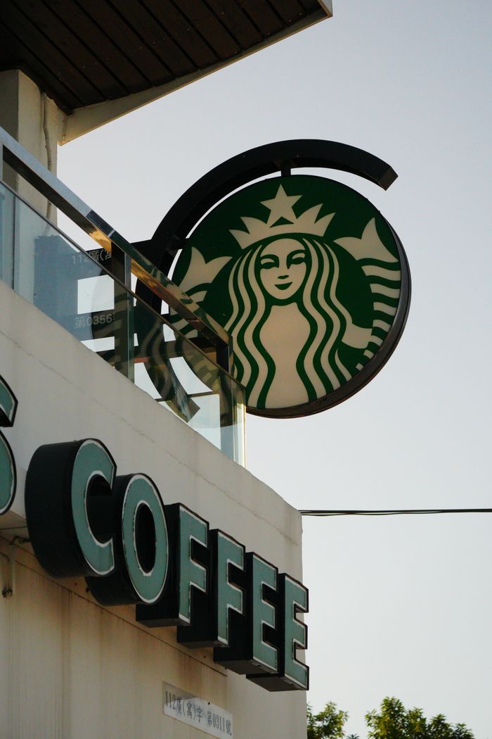 Iconic coffee shop sign on a building in a city setting.